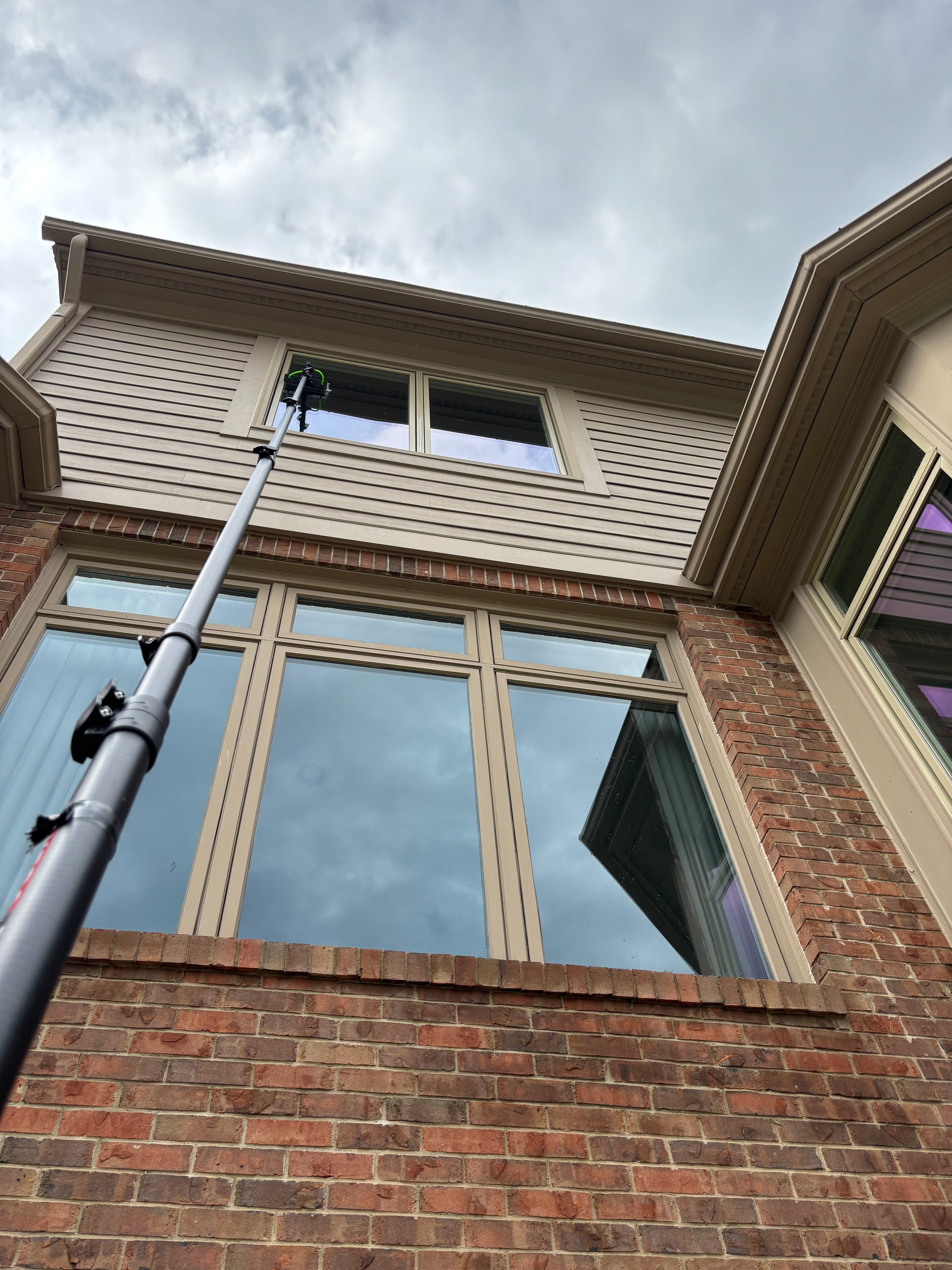 Water-fed pole reaching upper-story windows on a brick Bloomfield Hills home